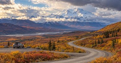 Editorial illustration of a vehicle by a winding road through autumn tundra toward Alaska mountains