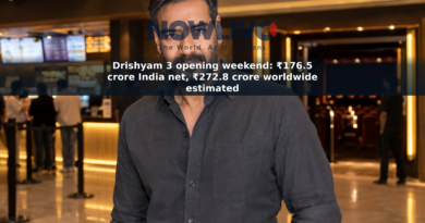 Staged editorial-style portrait of Ajay Devgn in a softly lit cinema foyer.