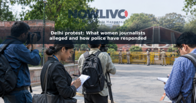 Journalists carrying cameras and notebooks near a police barricade in a New Delhi street scene.