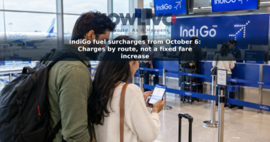 Travelers with luggage check a flight booking on a phone near an airport check-in counter.