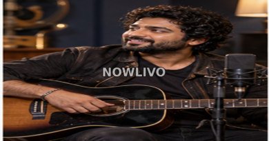 Musician seated with an acoustic guitar beside a recording microphone in a warmly lit studio.