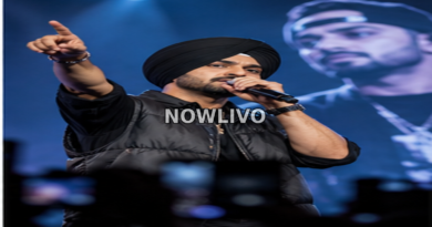 Punjabi singer in a black turban performing on stage with a microphone under blue concert lighting.