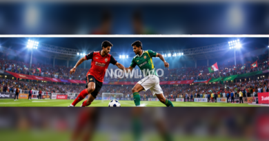 Two footballers in red and green kits contesting the ball under bright stadium lights