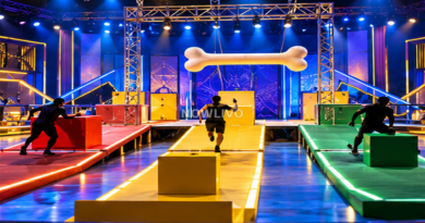 Conceptual blue and gold obstacle-course stage with colored lanes, a bone prop and anonymous contestants representing the Bigg Boss Telugu GOAT challenge; illustration. Centered NOWLIVO watermark.