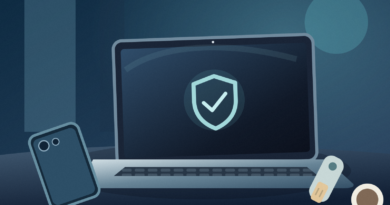 Text-free editorial illustration of a laptop with an abstract security shield, a turned-over phone and a physical security key on a dim blue desk