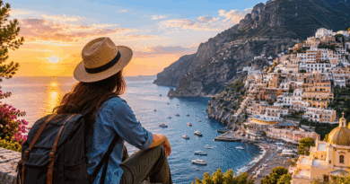 Traveller overlooking a steeply built Mediterranean coastal village with terraces and boats at sunset
