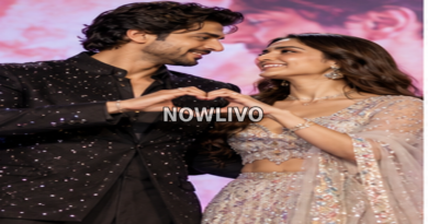 Stylish South Asian film-promotion couple posing on stage and forming a heart shape with their hands.